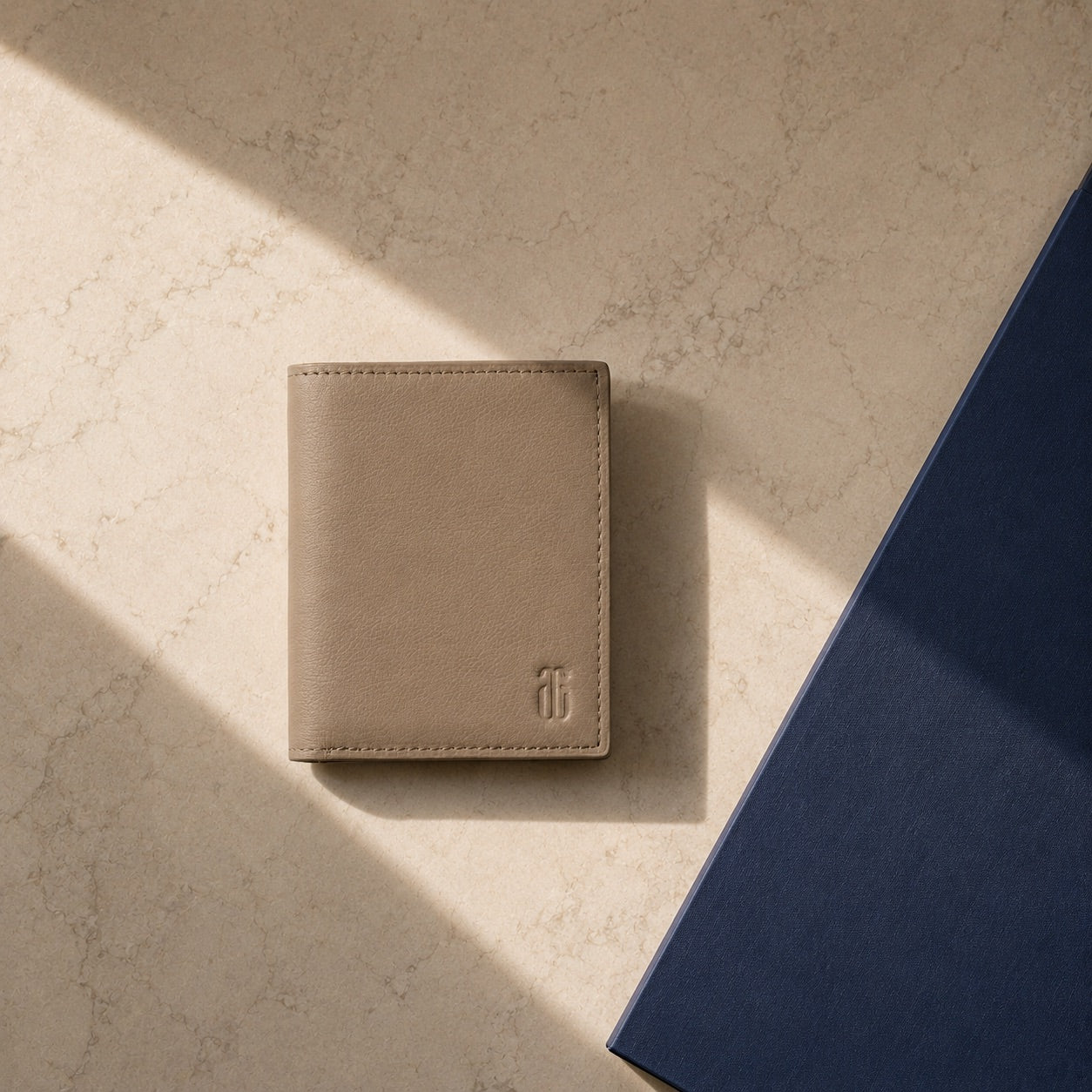 Beige leather wallet on a textured beige surface with a blue object partially visible.