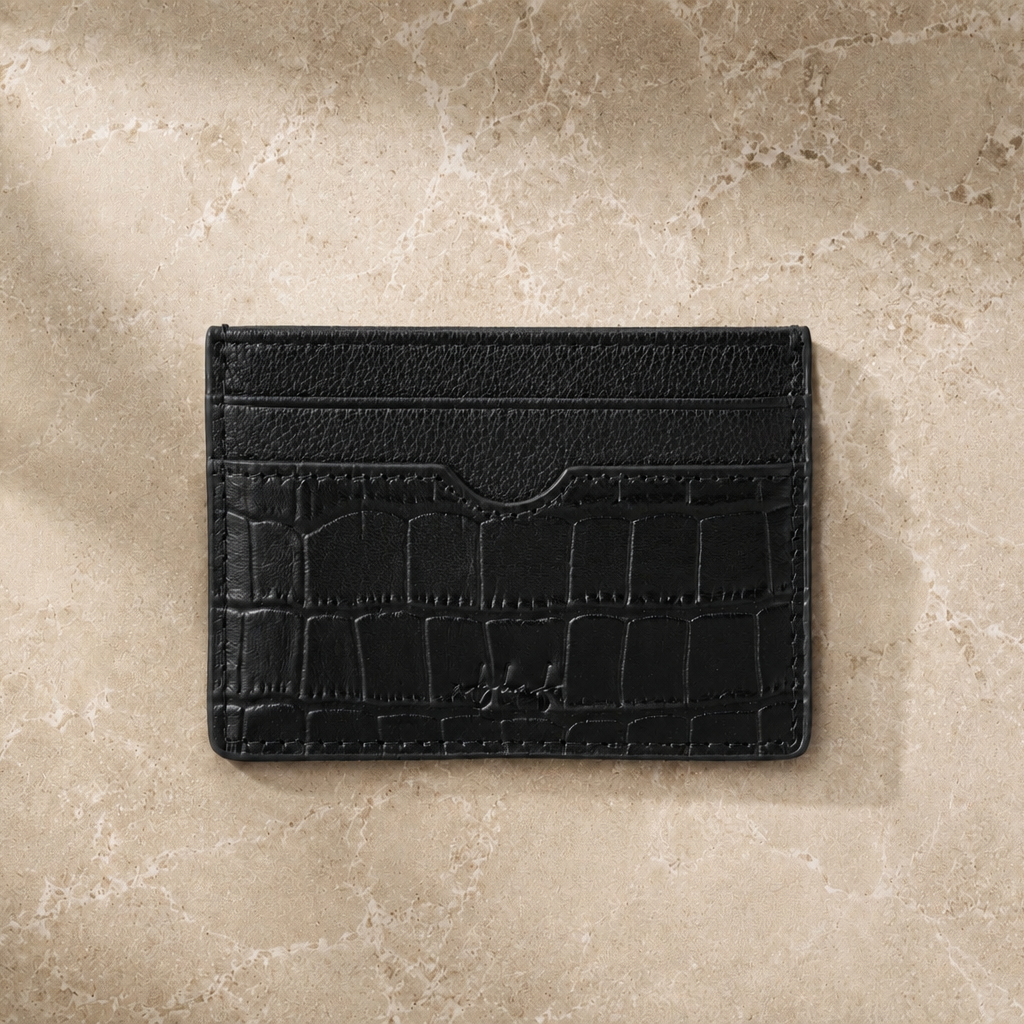 Black leather cardholder on a beige stone surface