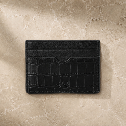 Black leather cardholder on a beige stone surface
