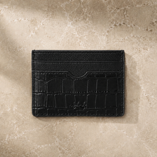 Black leather cardholder on a beige stone surface