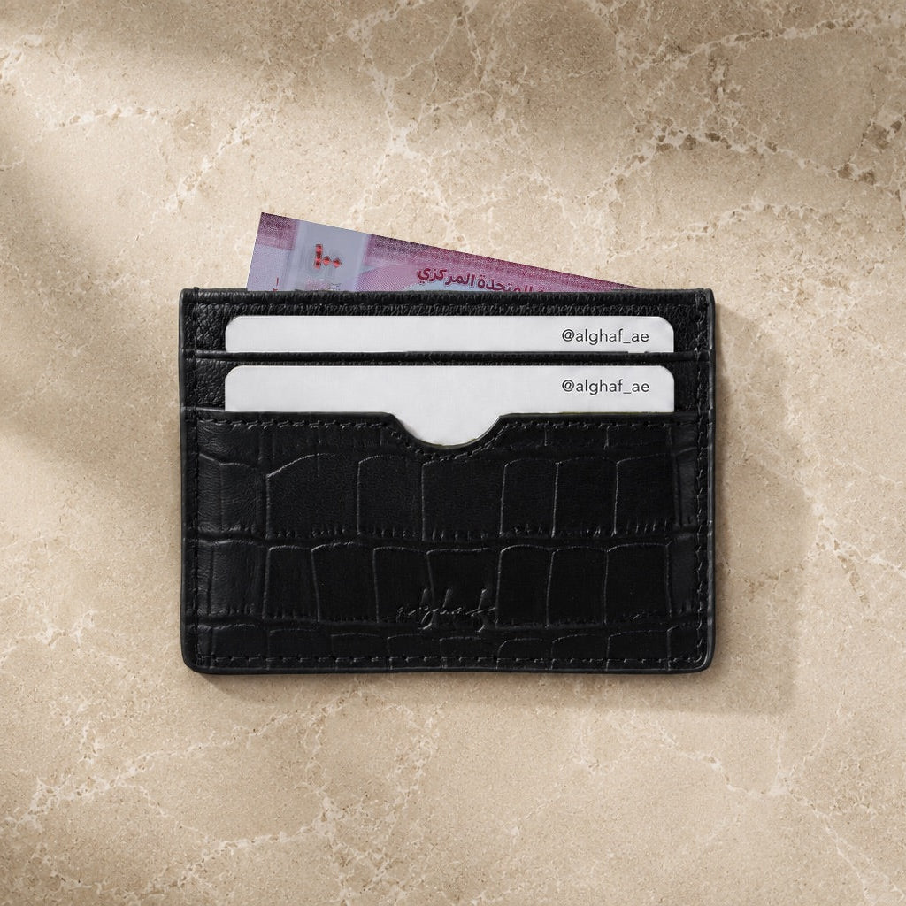 Black leather cardholder with cards on a beige surface