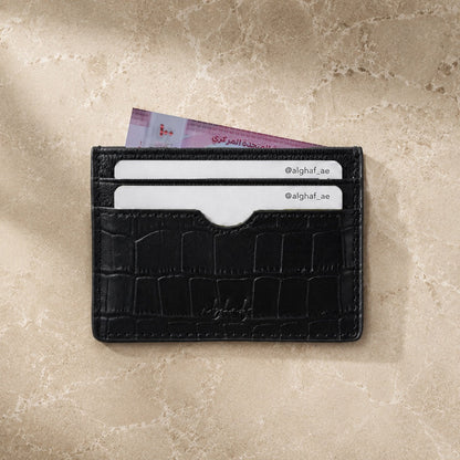 Black leather cardholder with cards on a beige surface