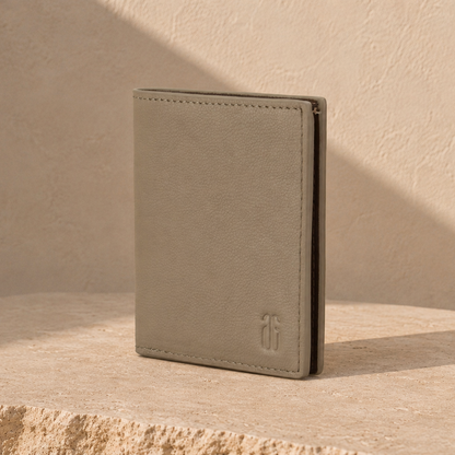 Beige leather wallet on a beige surface with a soft shadow