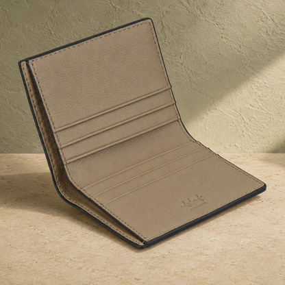 Beige leather wallet on a wooden surface with a greenish-brown background